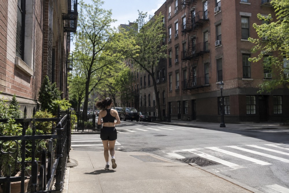 A Greenwich Village street corner with brick apartment buildings and a fire escape above a quiet intersection