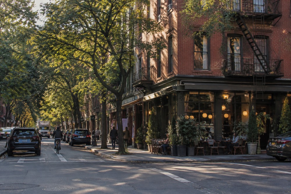 Corner apartment building on a tree-lined Greenwich Village street with brick facades and a restaurant on the ground floor