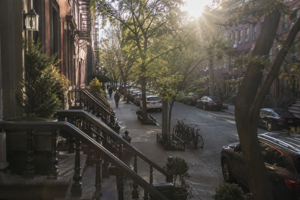 Narrow tree-lined street in the West Village with brick row houses and parked bicycles