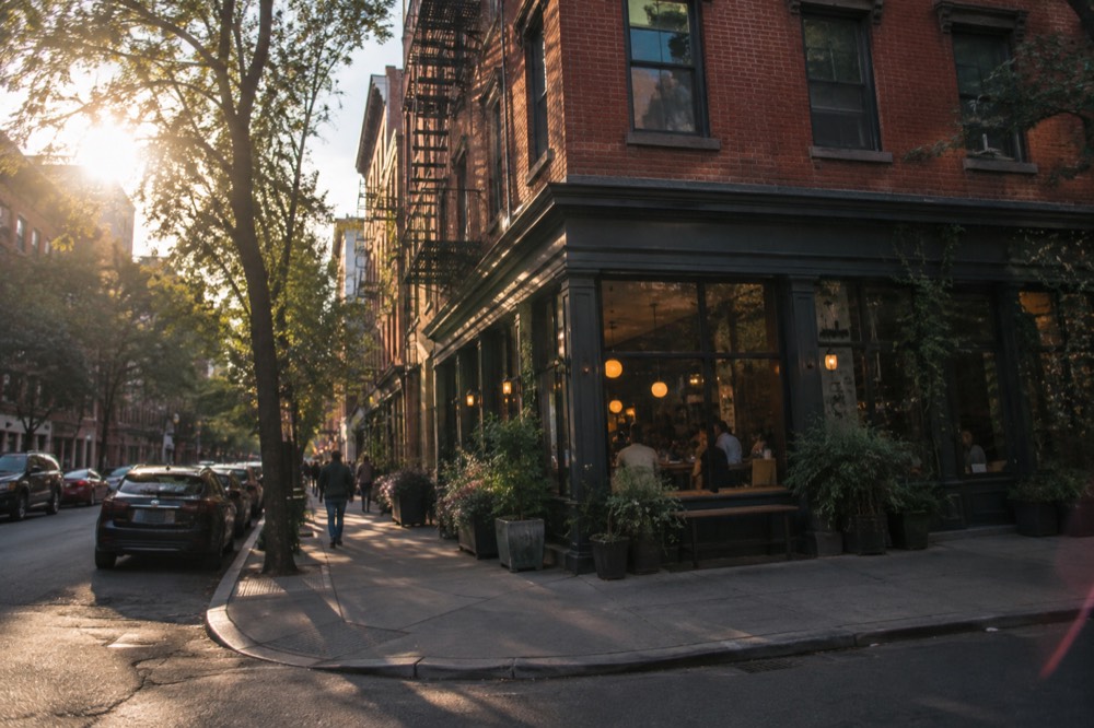 A brick corner building with a restaurant on the ground floor on a quiet street in Greenwich Village
