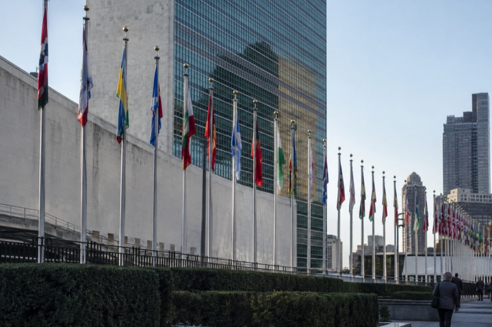The row of member state flagpoles in front of the United Nations Headquarters on a clear morning