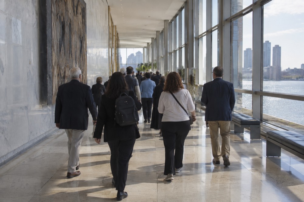 A tour group walking through a bright interior corridor of the United Nations Headquarters