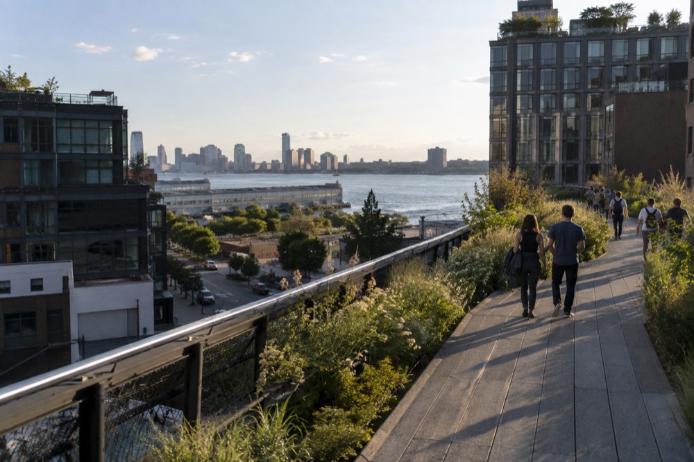 Visitors walking the High Line elevated park on a clear afternoon with Hudson River views