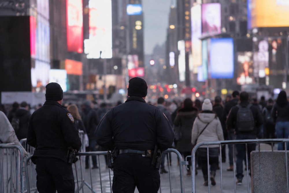 Police officers managing crowd barriers in Times Square on a cold winter evening