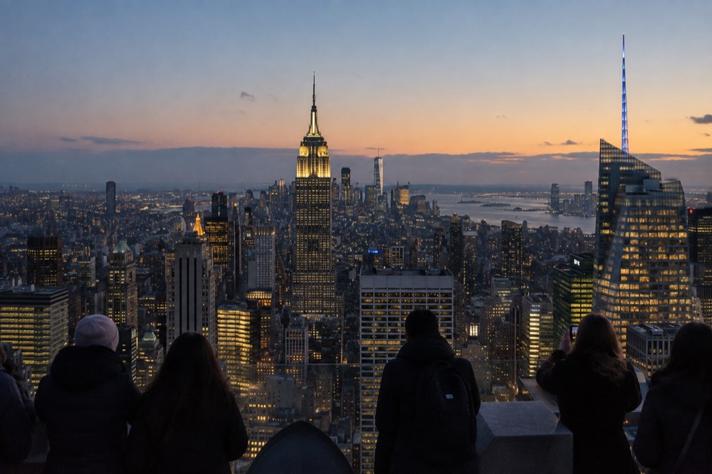 An observation deck at dusk with the Manhattan skyline glowing under a clear winter sky