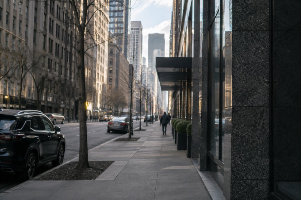 A quiet Midtown side street in the morning with office towers above and an empty sidewalk
