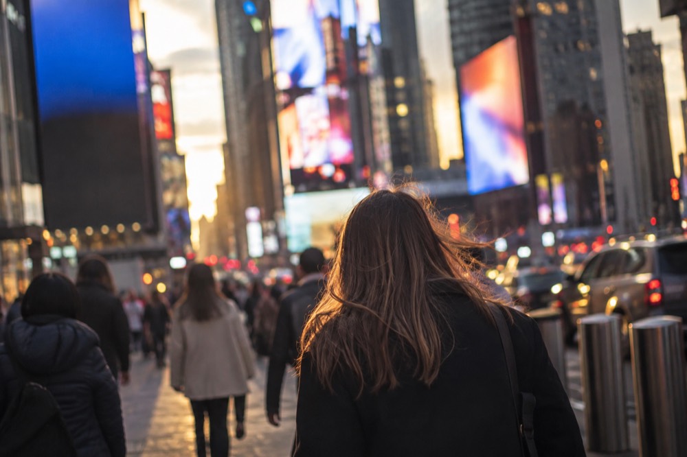 Times Square at dusk with illuminated billboards and crowds crossing the street