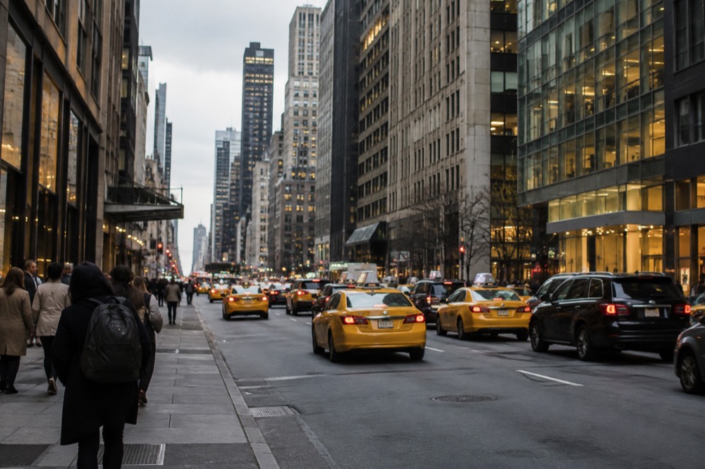 Yellow taxis and cars filling a busy Manhattan avenue between tall buildings
