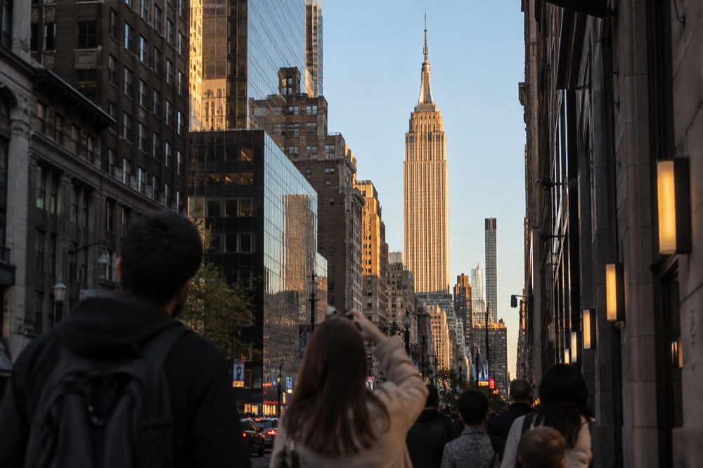 Visitors looking up at the Empire State Building from a Midtown street