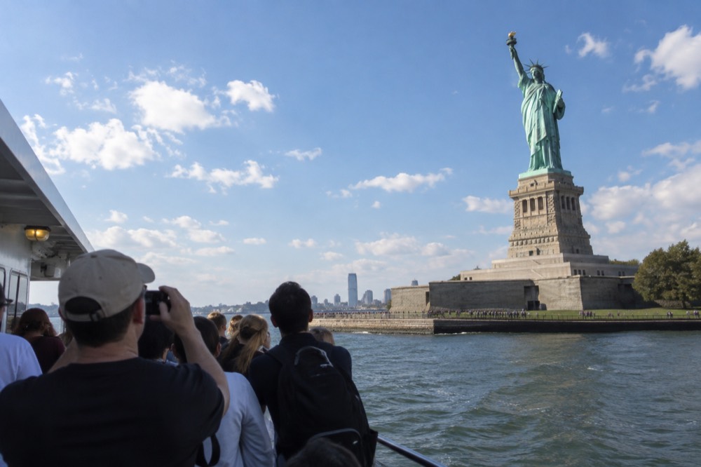 A sightseeing boat passing the Statue of Liberty in New York Harbor