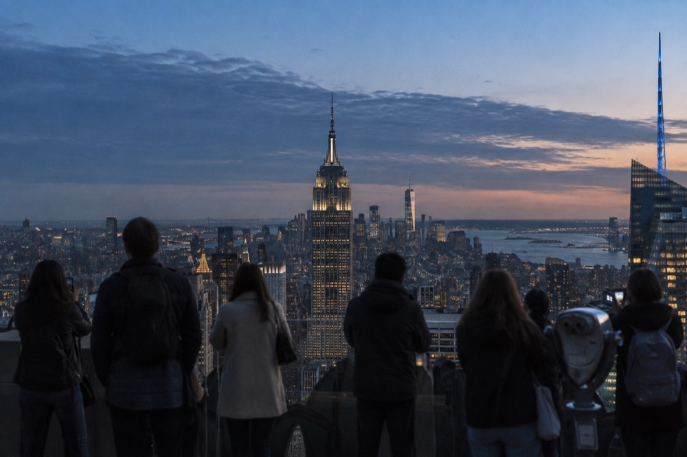 Visitors at a rooftop observation deck looking out over the Manhattan skyline