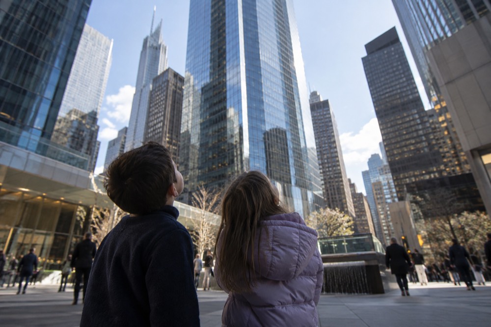 Two children look up at the glass towers surrounding a Midtown plaza