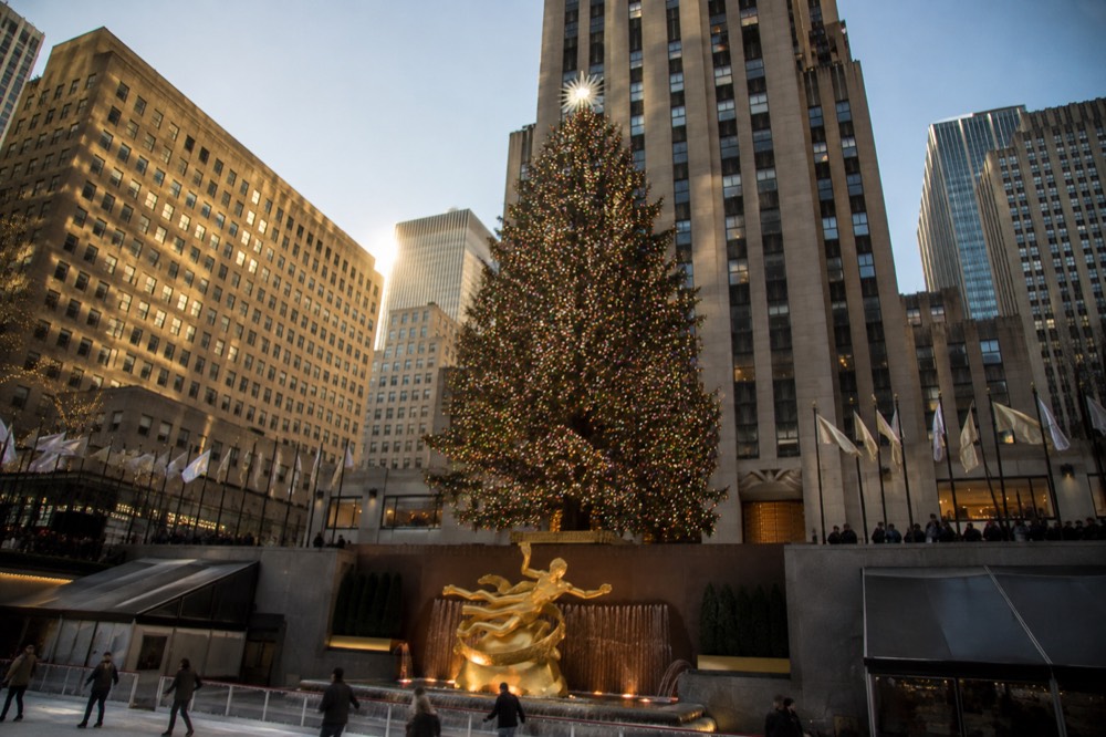 Rockefeller Center Christmas tree glowing above the ice rink with skyscrapers behind it