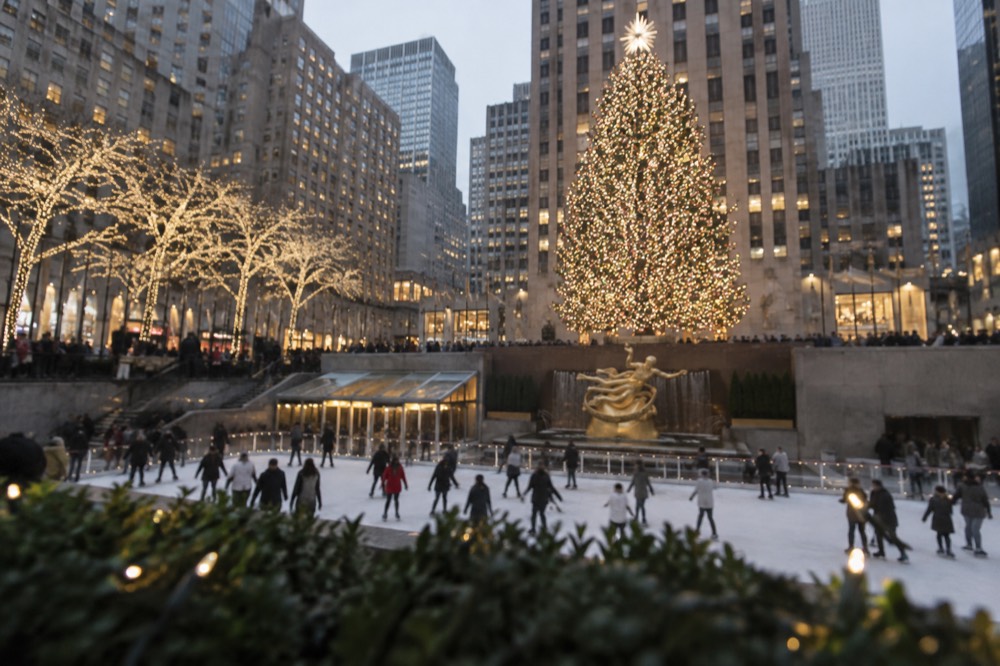 The Rockefeller Center ice rink and Christmas tree surrounded by buildings and visitors in the evening