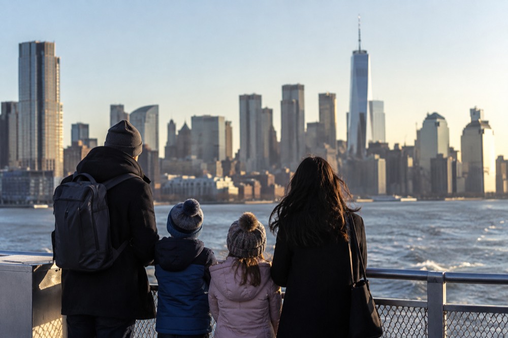 Parents and two children looking up at the Manhattan skyline from a ferry deck