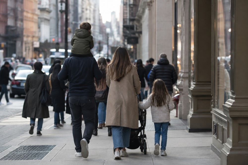 A family walking through a crowded SoHo street in daylight with shops open along both sides