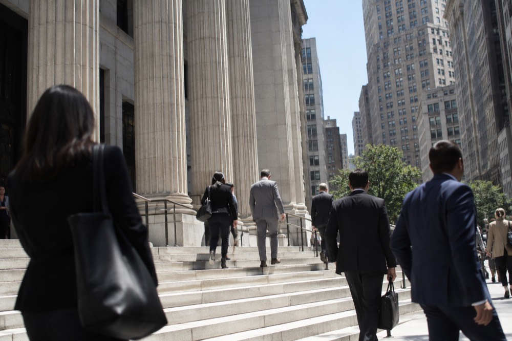 The steps of a New York courthouse on a weekday morning with people walking past