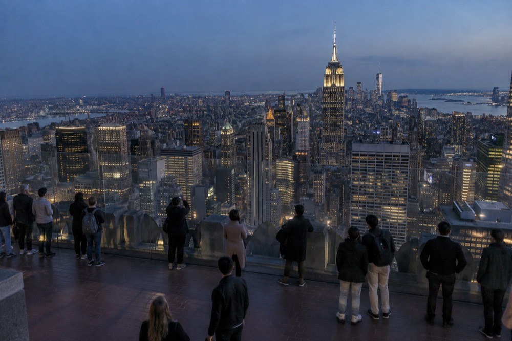 Visitors looking at the Manhattan skyline from an observation deck on a clear day
