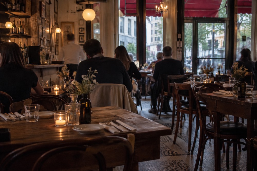 A candlelit Italian restaurant dining room with rustic wooden tables and a tiled floor
