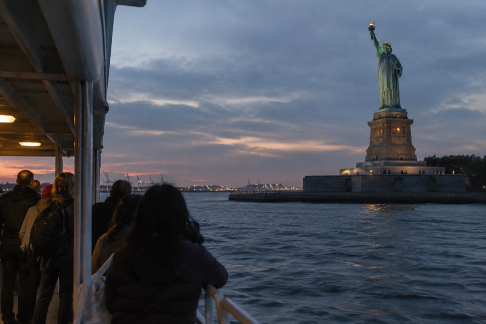 A sightseeing boat passing close to the Statue of Liberty in New York Harbor