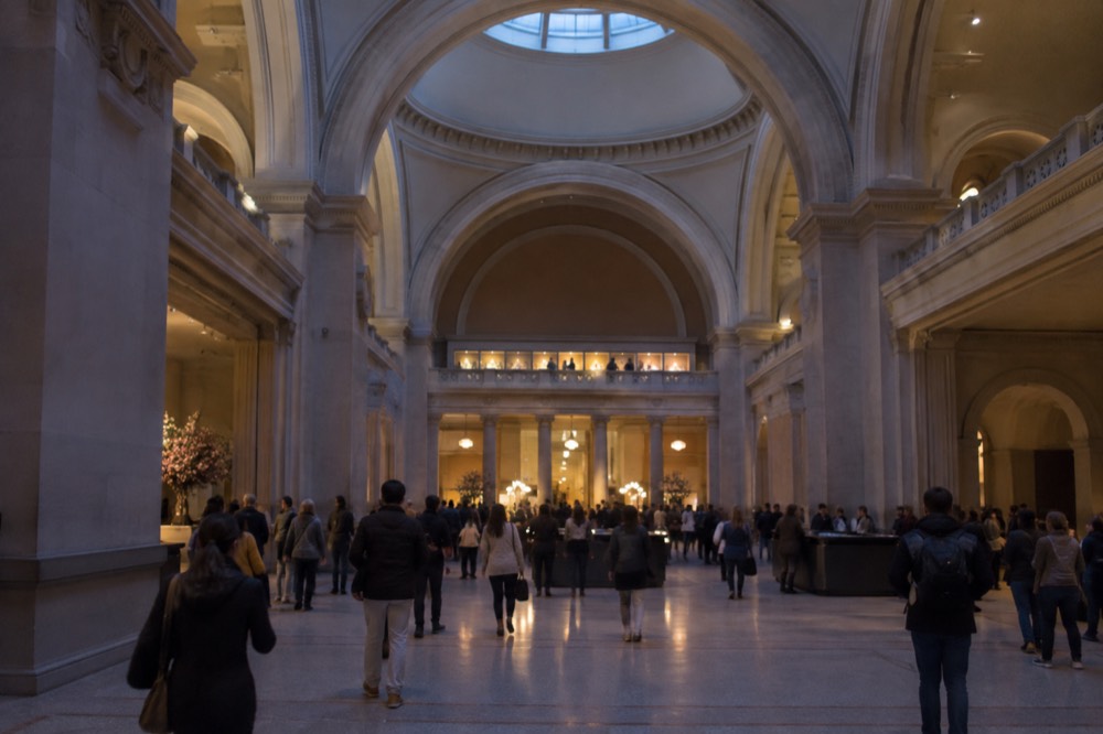 The Great Hall of the Metropolitan Museum of Art with visitors gathered beneath its high arched ceiling