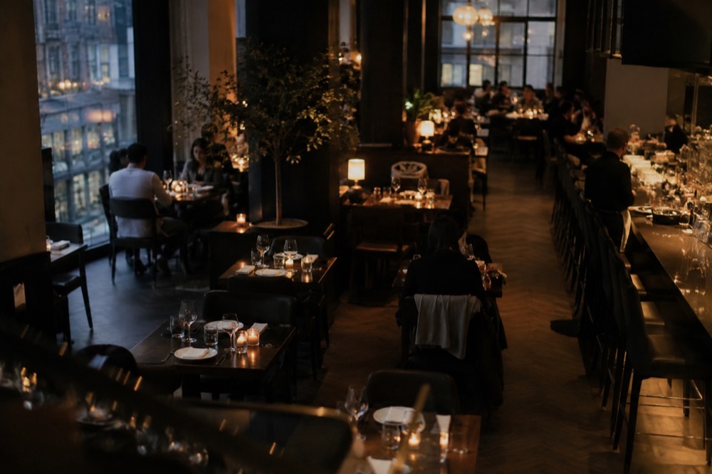 A sleek restaurant dining room with dark wood tables and soft lighting in a downtown Manhattan evening