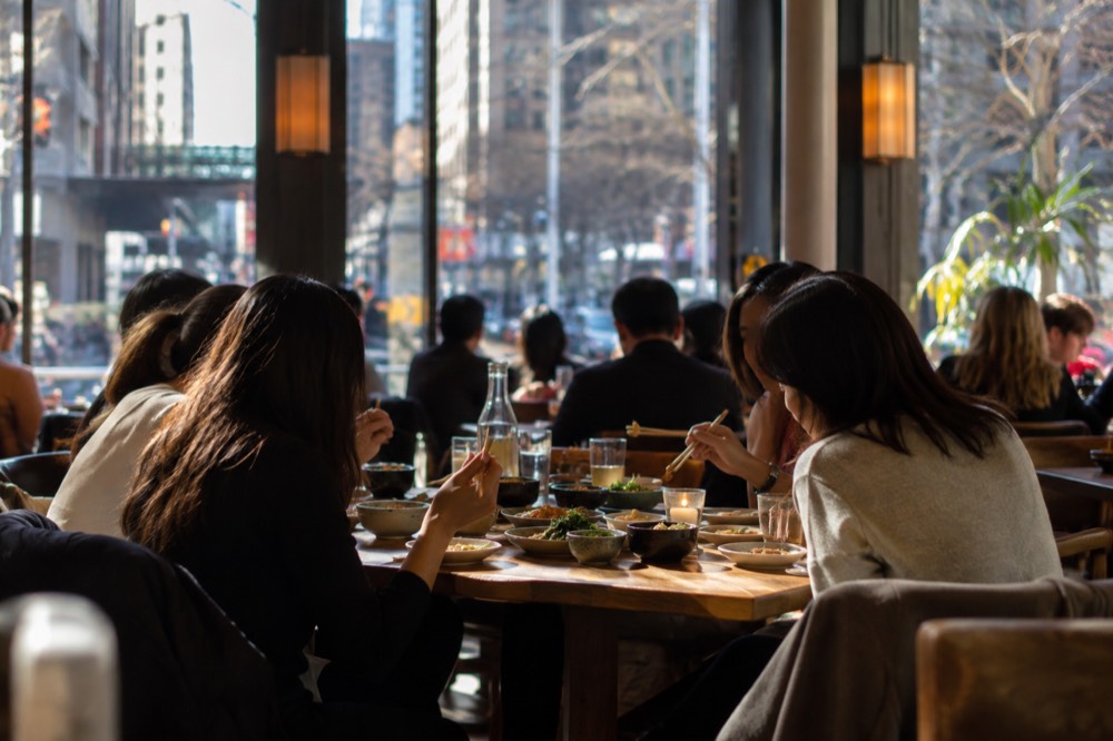 A dining table with shared small plates and chopsticks in a warmly lit restaurant