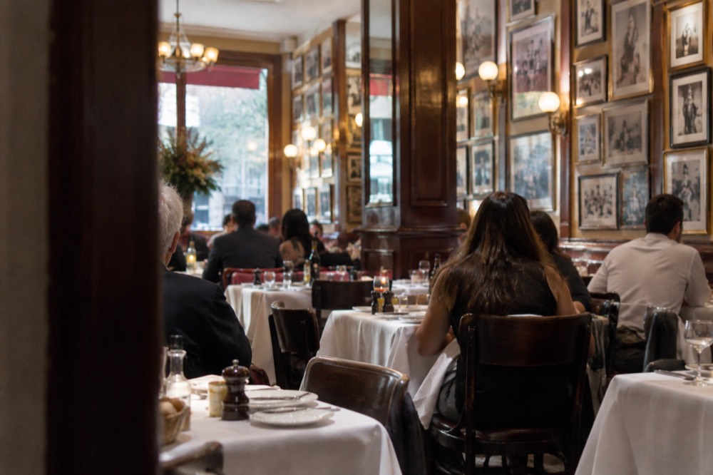 A classic red-sauce Italian restaurant dining room with white tablecloths and framed photographs on the walls