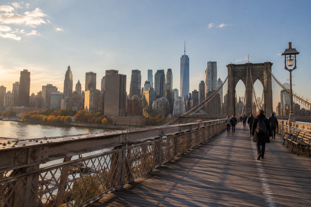 A pedestrian walkway spanning a wide river with tree-lined banks in fall colors