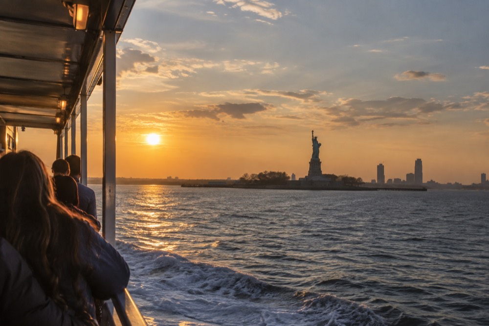 A passenger ferry crossing New York Harbor with the Statue of Liberty in the distance