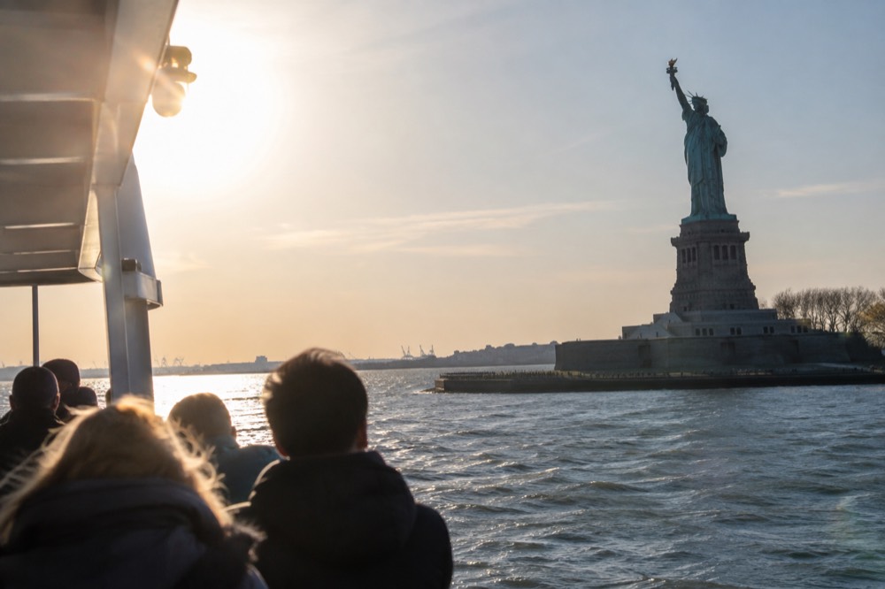 A ferry boat passing close to the Statue of Liberty in New York Harbor on a clear day