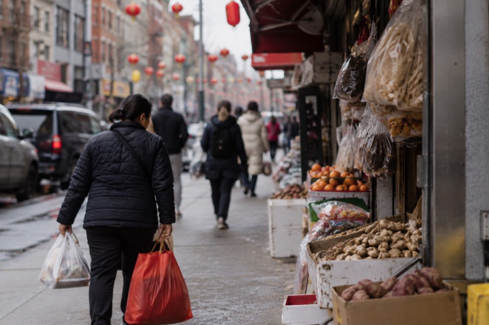 Narrow Chinatown sidewalk with hanging shop signs in English and Chinese characters