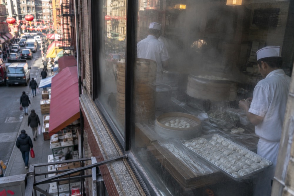 Cooks preparing dumplings behind a steamy restaurant window in Chinatown