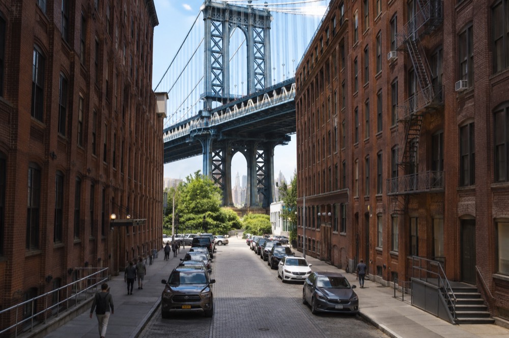 The Manhattan Bridge rising above cobblestone streets and old brick warehouses in Dumbo, Brooklyn