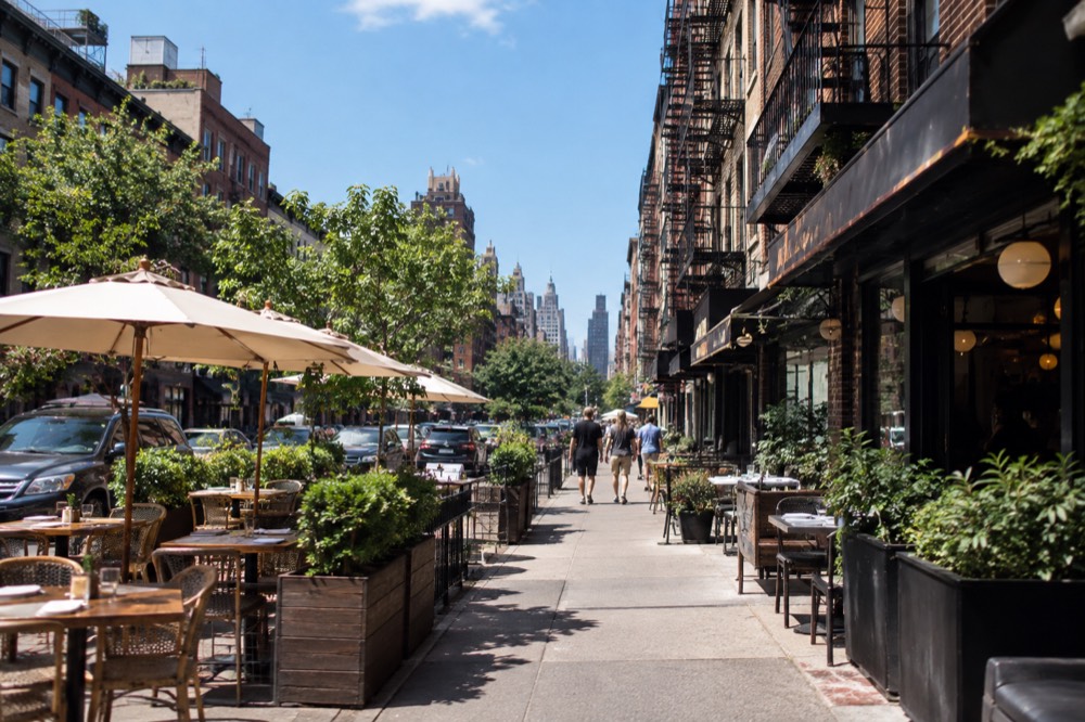 Diners and small restaurants with lit signs along a busy East Village avenue in the evening