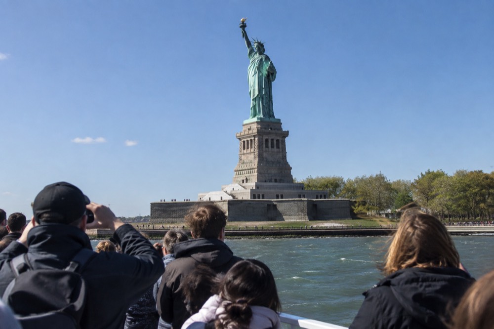 A ferry passing close to the Statue of Liberty in New York Harbor
