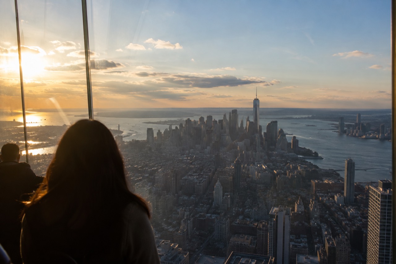 The skyline of Lower Manhattan seen across the harbor, with One World Trade Center rising above older towers