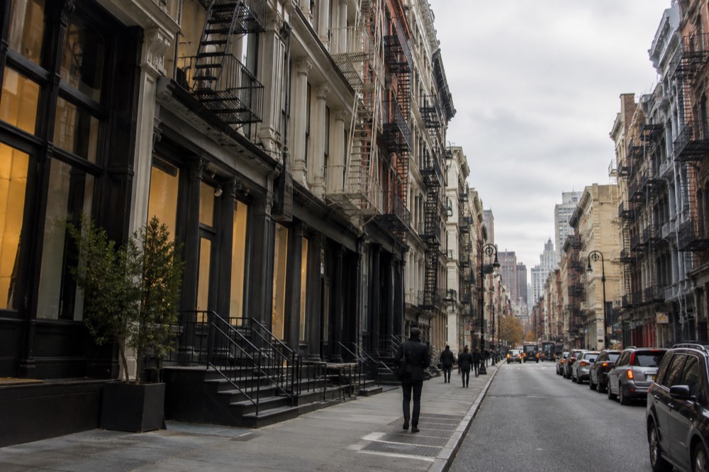 Row of cast-iron building facades with fire escapes on a SoHo street