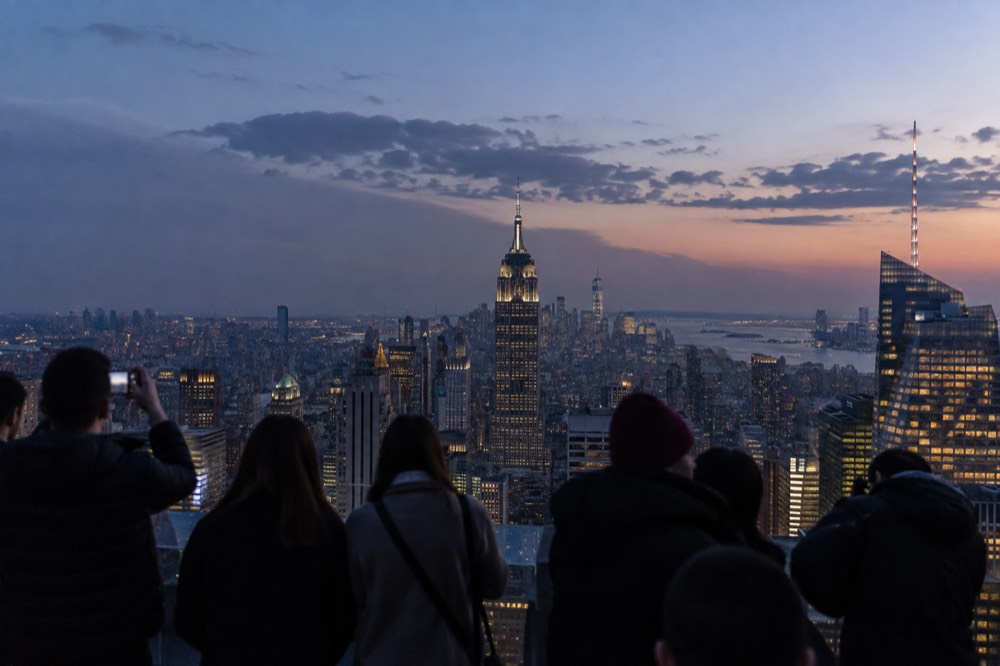 Visitors standing on an outdoor observation deck high above the Manhattan skyline