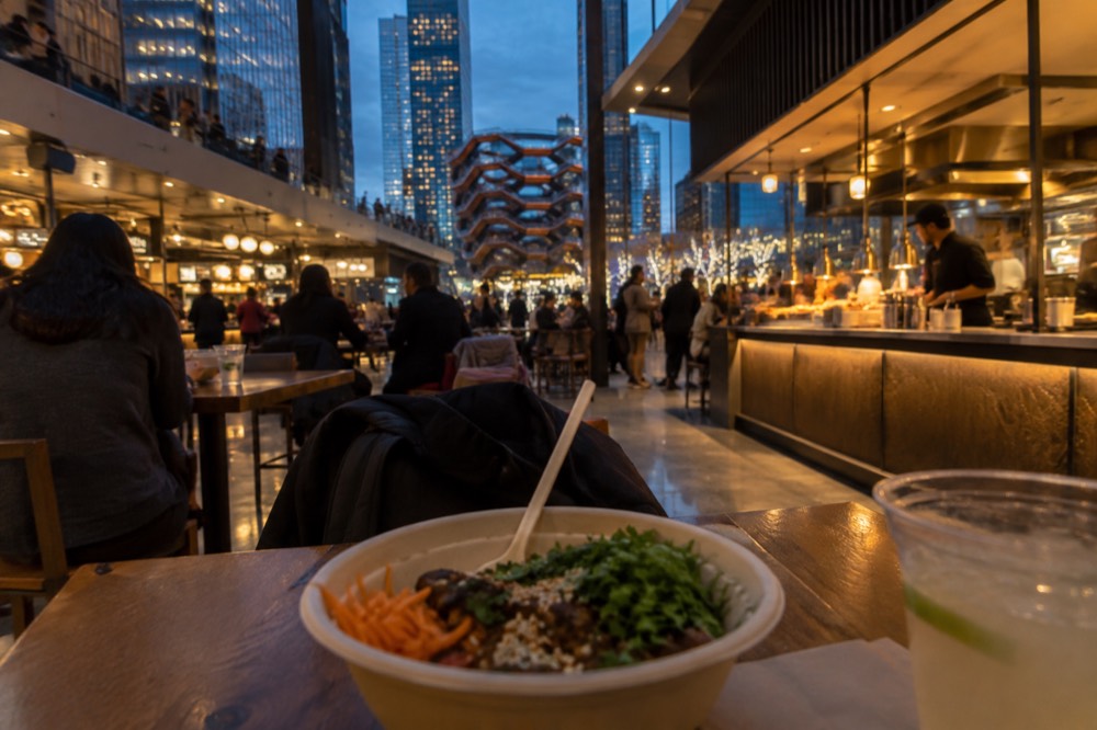 Busy food hall with counters serving different cuisines under warm lighting