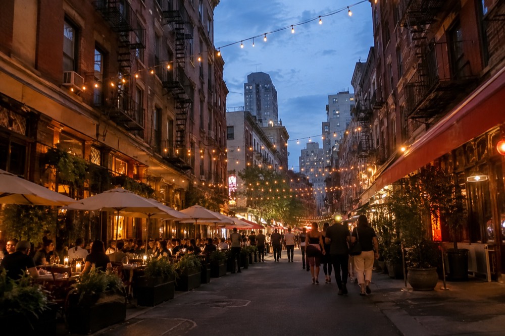 Evening view of Mulberry Street with string lights and diners at outdoor tables
