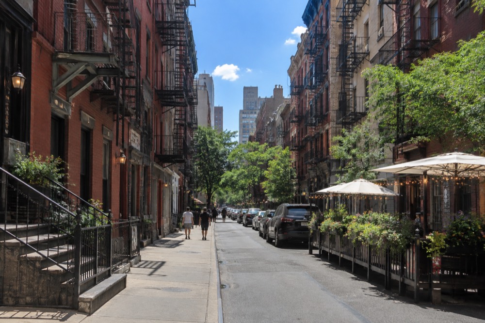 A narrow Little Italy side street with old brick buildings and fire escapes