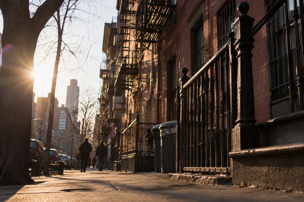 An historic Lower East Side tenement building with a metal fire escape and worn brick facade in late afternoon light