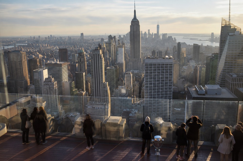 Visitors on an open-air observation deck looking out over Manhattan towers