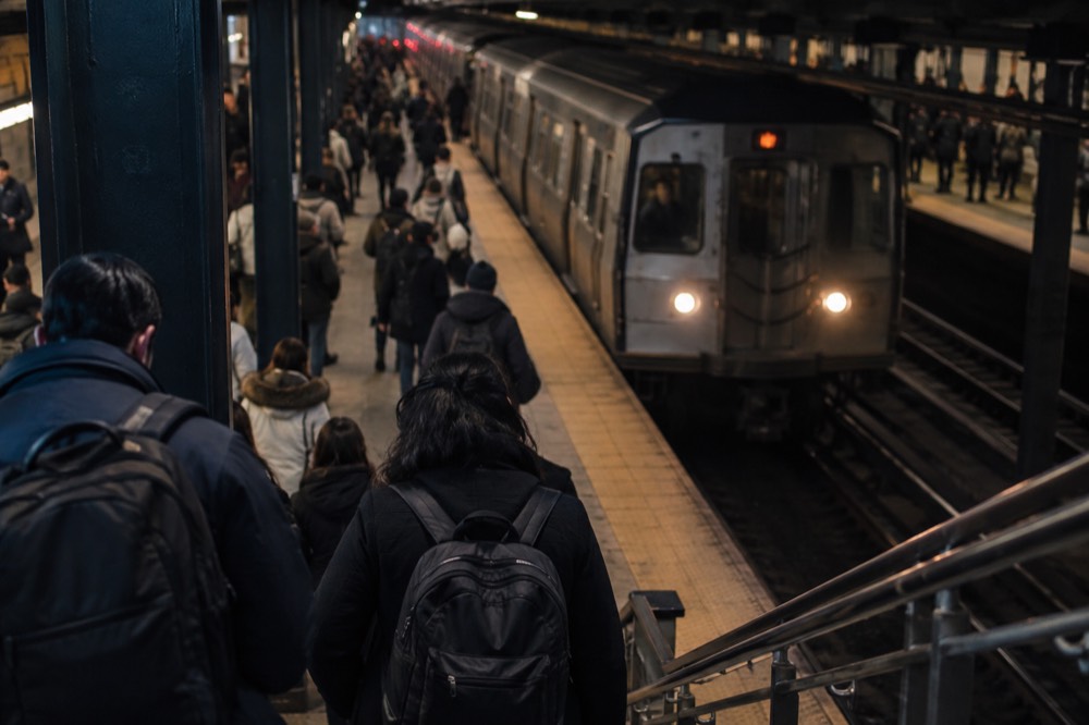 A crowded subway platform with a train pulling in beneath Midtown