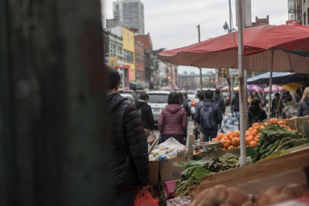 Shoppers and food vendors on a busy street in Flushing, Queens