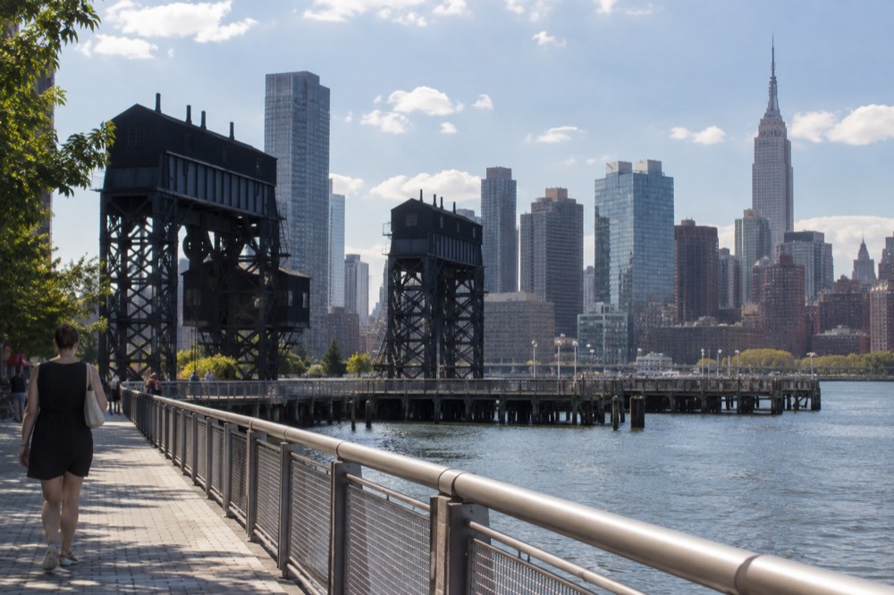 Waterfront walkway at Gantry Plaza State Park with gantry cranes and the Midtown skyline