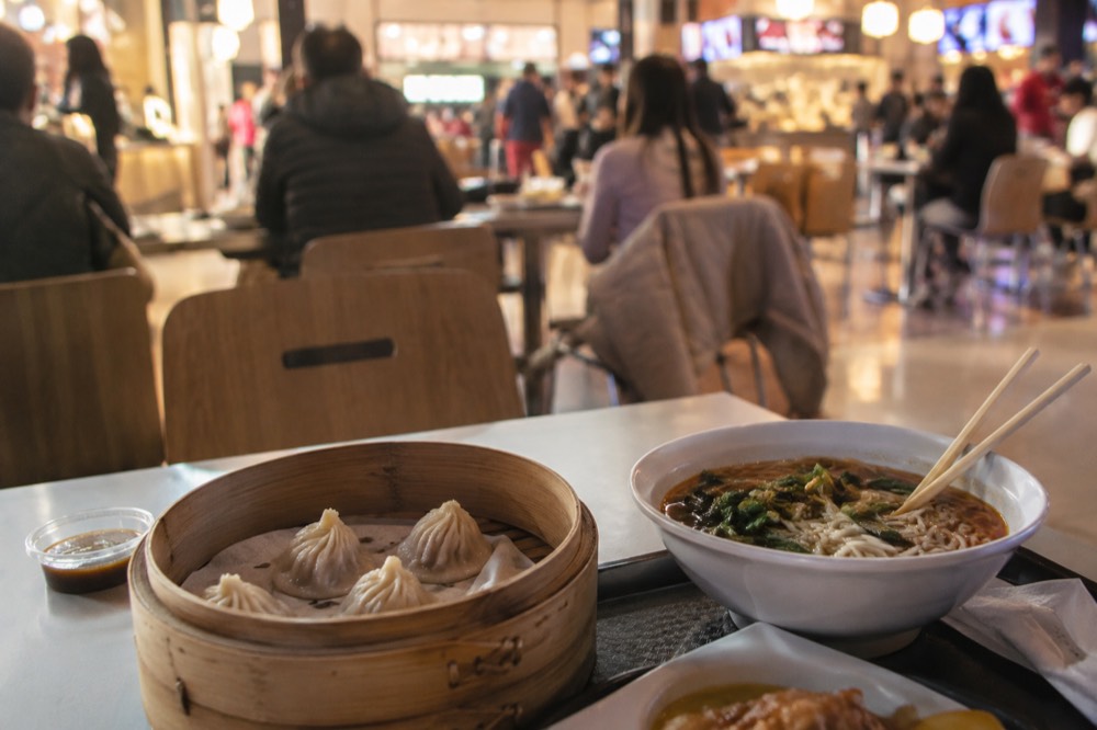 Dumplings and noodles on a table in a Flushing food court
