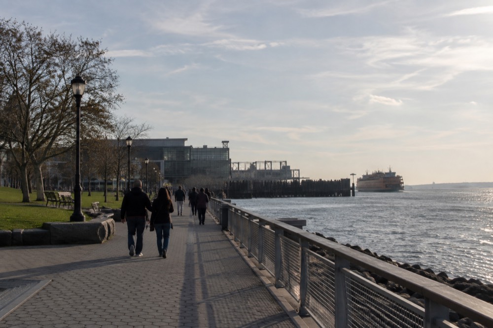 Visitors walking along the waterfront esplanade near St George Terminal on a clear day