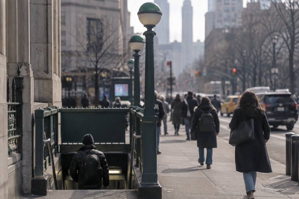 A subway entrance on a bright Lower Manhattan street corner